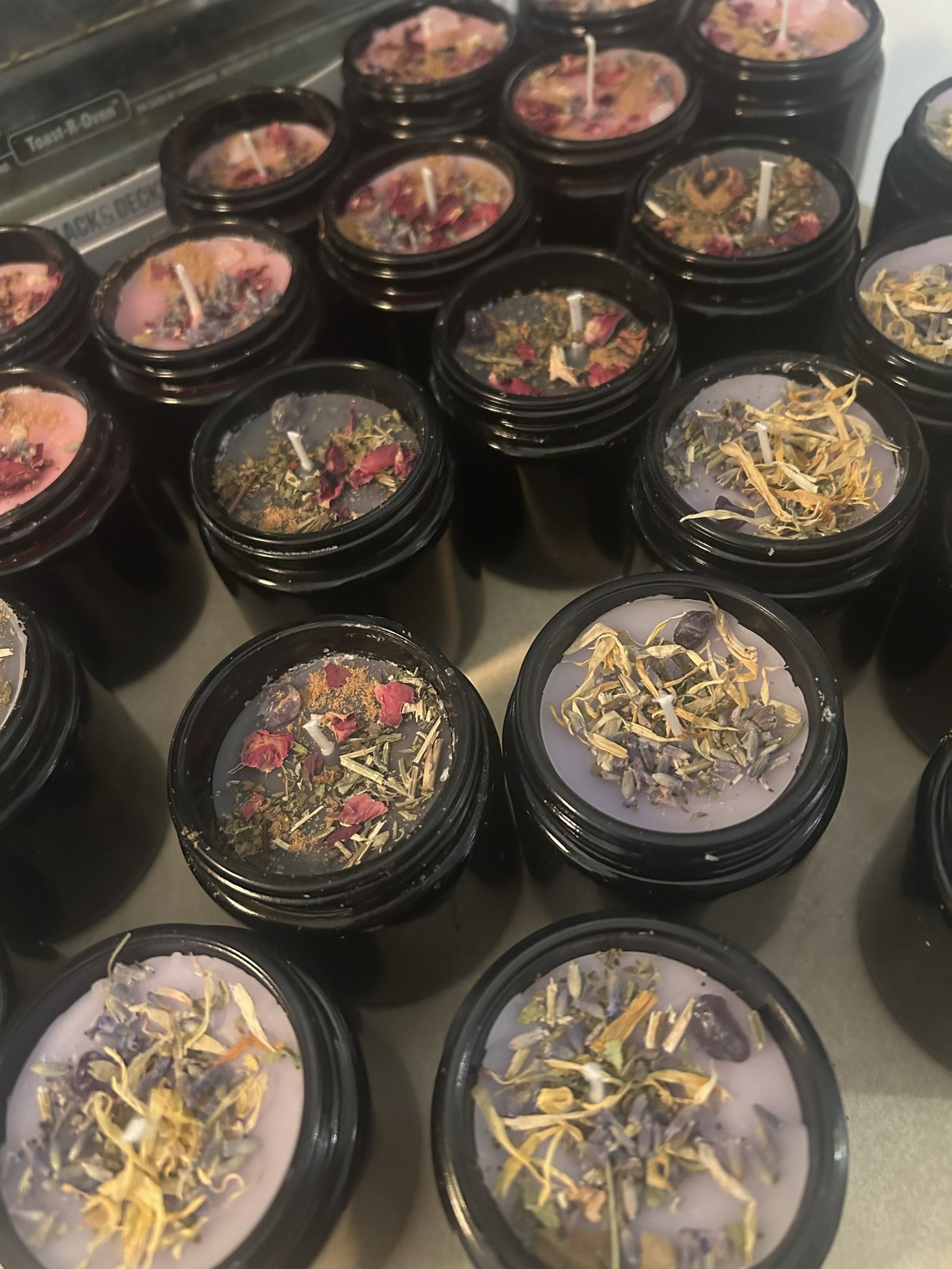 Small-batch herbal candles topped with dried flowers and botanicals